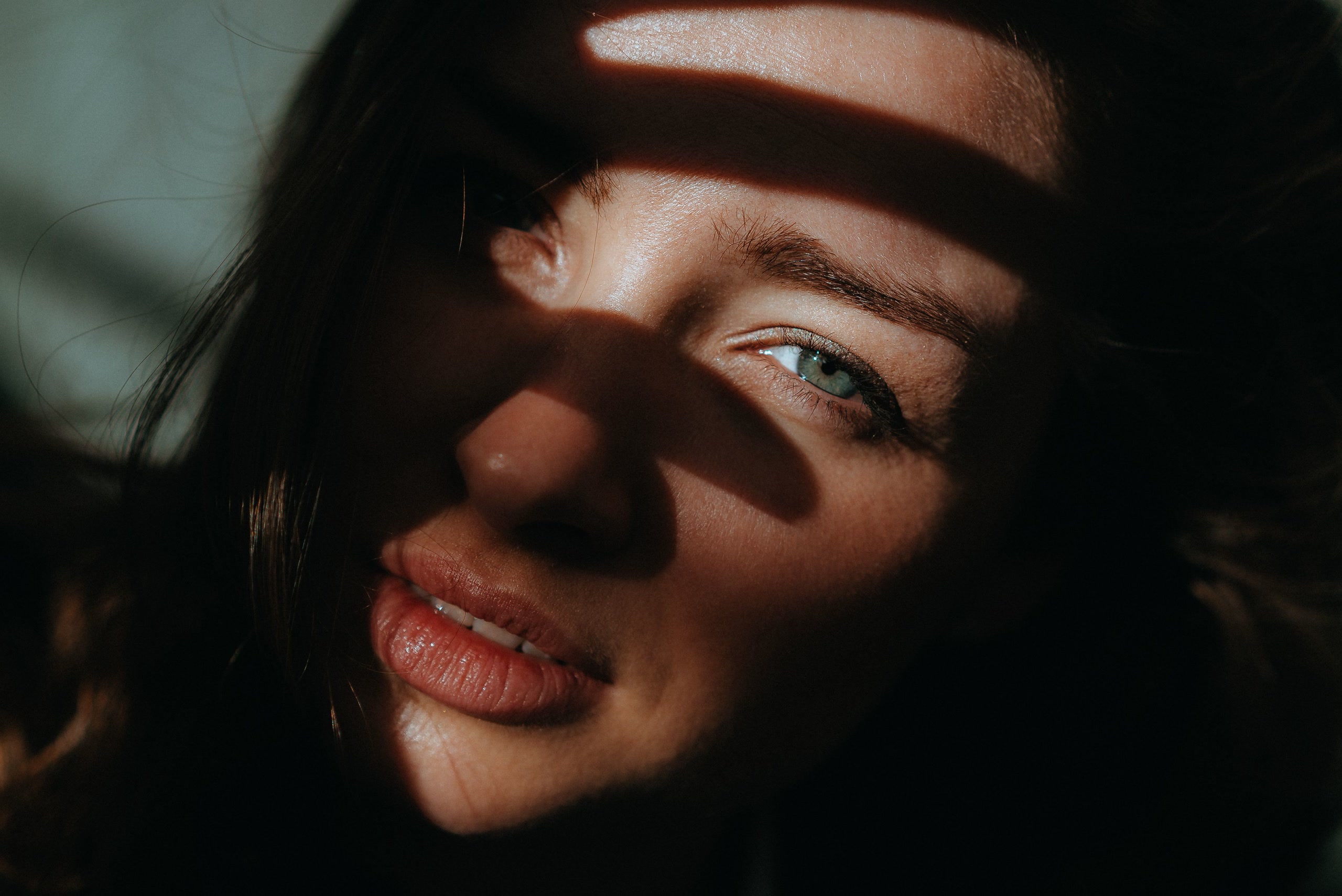 Close portrait of a woman's face lit by dappled natural sunlight